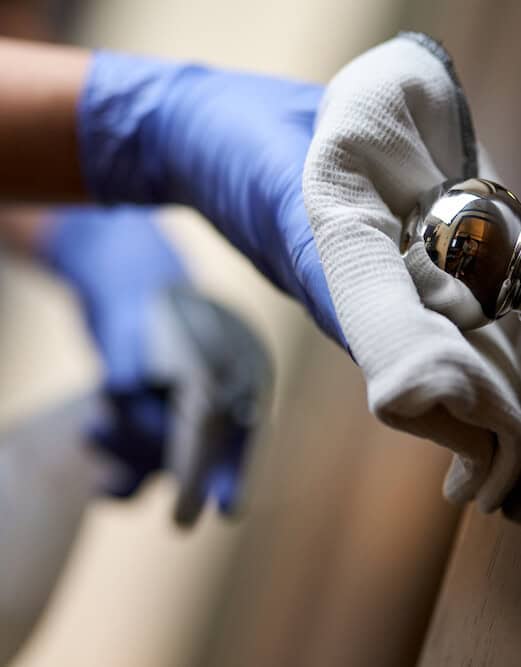 hand wiping the door handle using a cloth