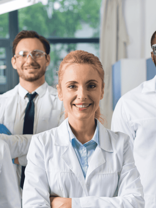 group of men and women lab technicians smiling wearing white coats